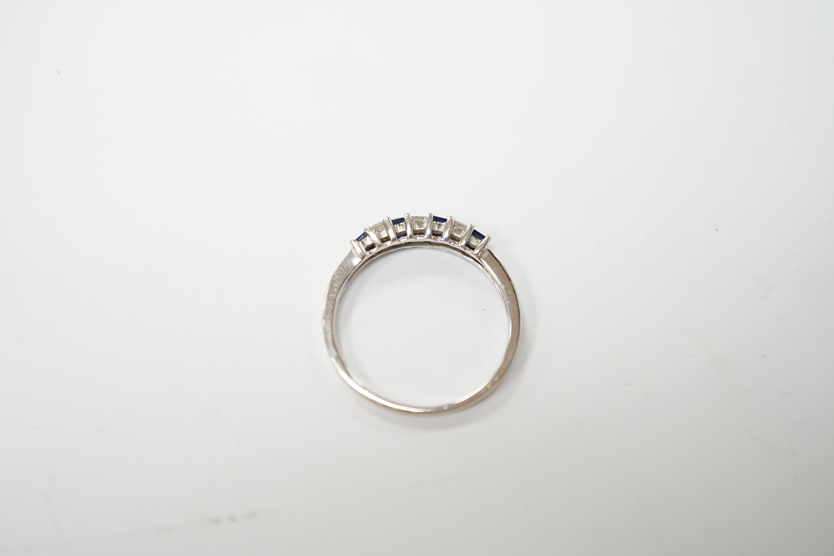 A modern 18k and plat, sapphire and diamond set seven stone half hoop ring, size O, gross weight 1.8 grams.